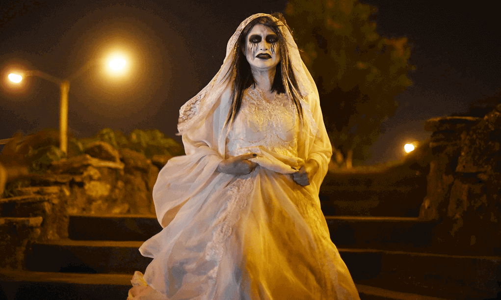 La gente observa a un actor disfrazado de "La Llorona”, un personaje del performance "Leyendas de Guatemala" en el barrio Cerrito del Carmen, antes de la celebración del Día de Todos los Santos en la ciudad de Guatemala, el 31 de octubre de 2015. Imagen de Johan Ordonez/AFP vía Getty Images