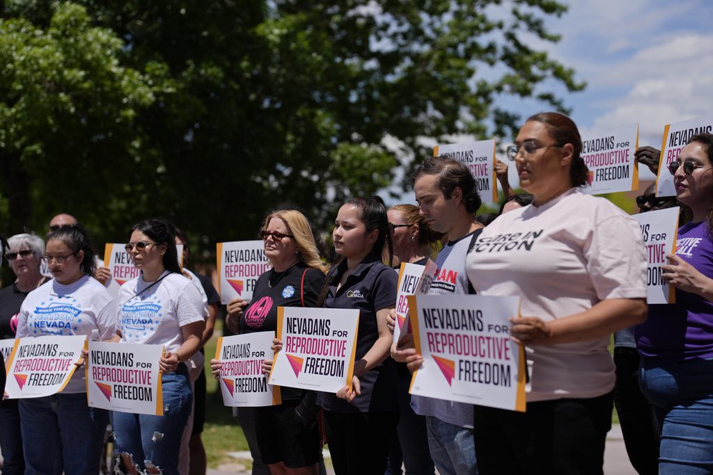 FILE - People hold signs during a news conference by Nevadans for Reproductive Freedom, Monday, May 20, 2024, in Las Vegas. At least four states will have abortion-related ballot questions in November's election and there's a push to get them before voters in several others. (AP Photo/John Locher, File)