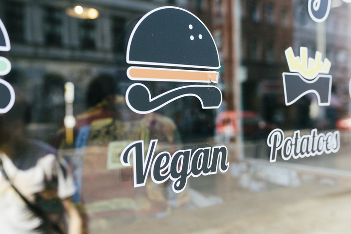 A vegan sign and logo on a burger restaurant window.