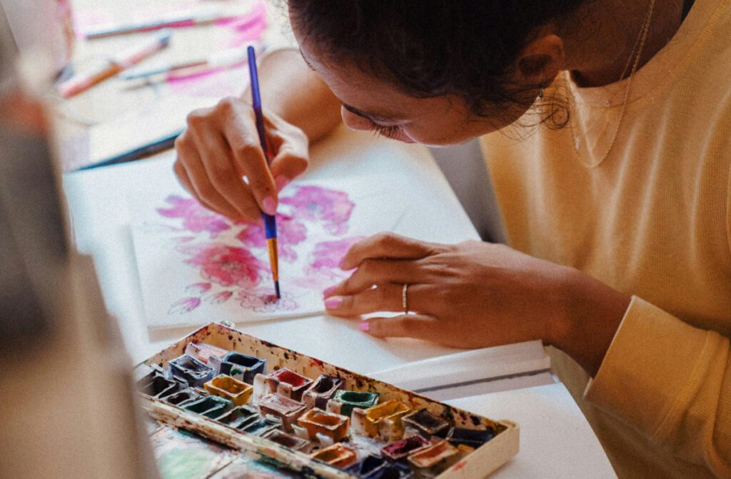 Young female artist with her head down, painting with a paint brush.