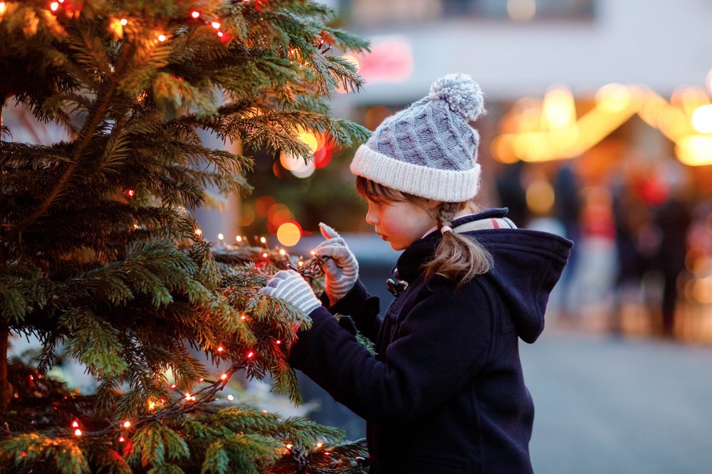 Little cute kid girl having fun on traditional Christmas market during strong snowfall.