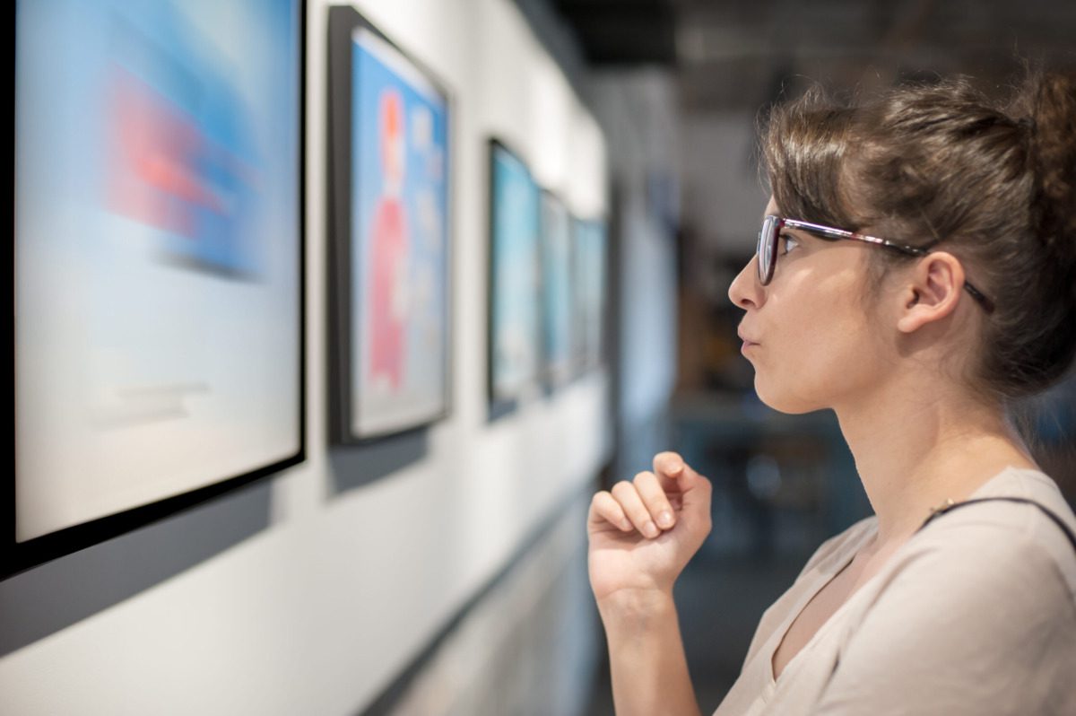 woman in glasses observes art in a museum