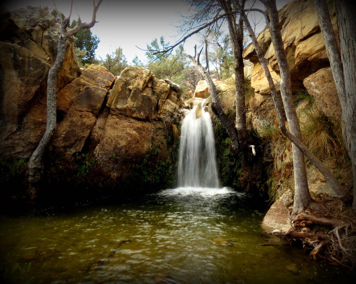 a small waterfall cascades into a body of water surrounded by rocks